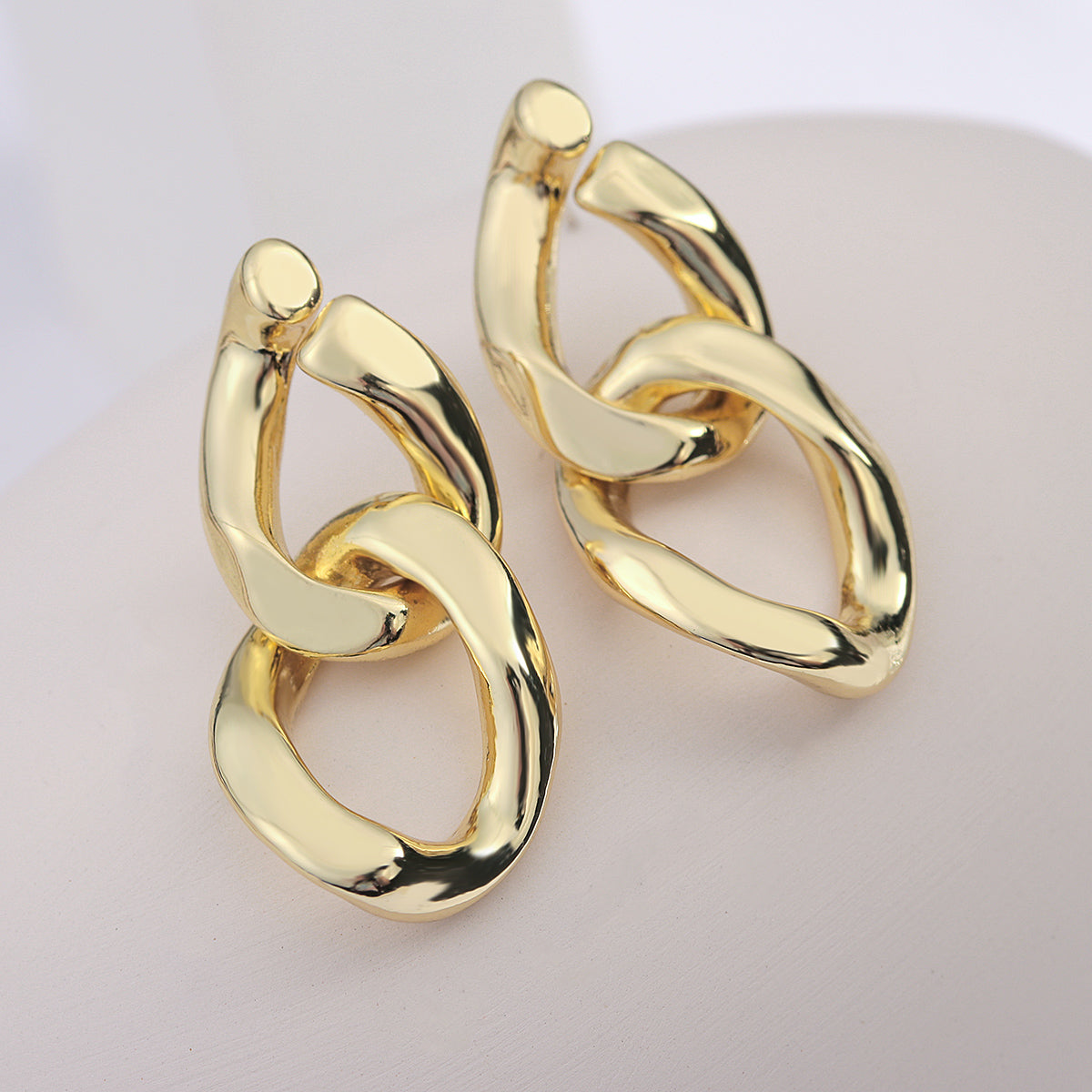 House of Royal Eva small cuban link gold earrings on plain background close up
