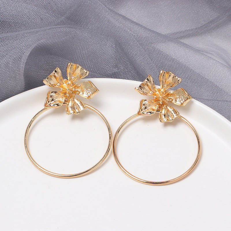 House of Royal Carmelle gold hoop earrings with flower product image on plate and fabric