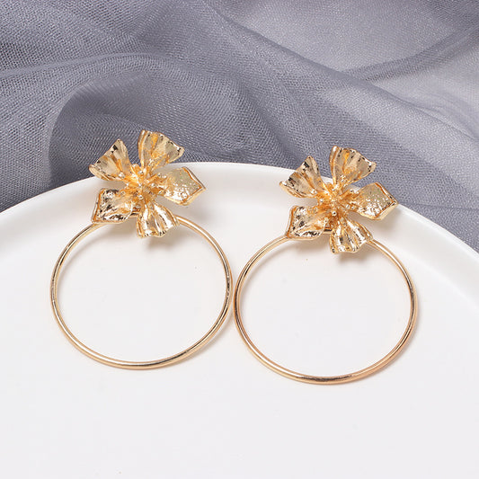 House of Royal Carmelle gold hoop earrings with flower product image on plate and fabric