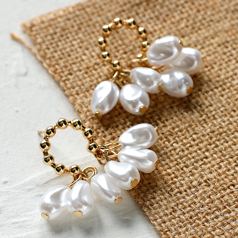 House of Royal Chloe small pearl and gold earrings on fabric background close up